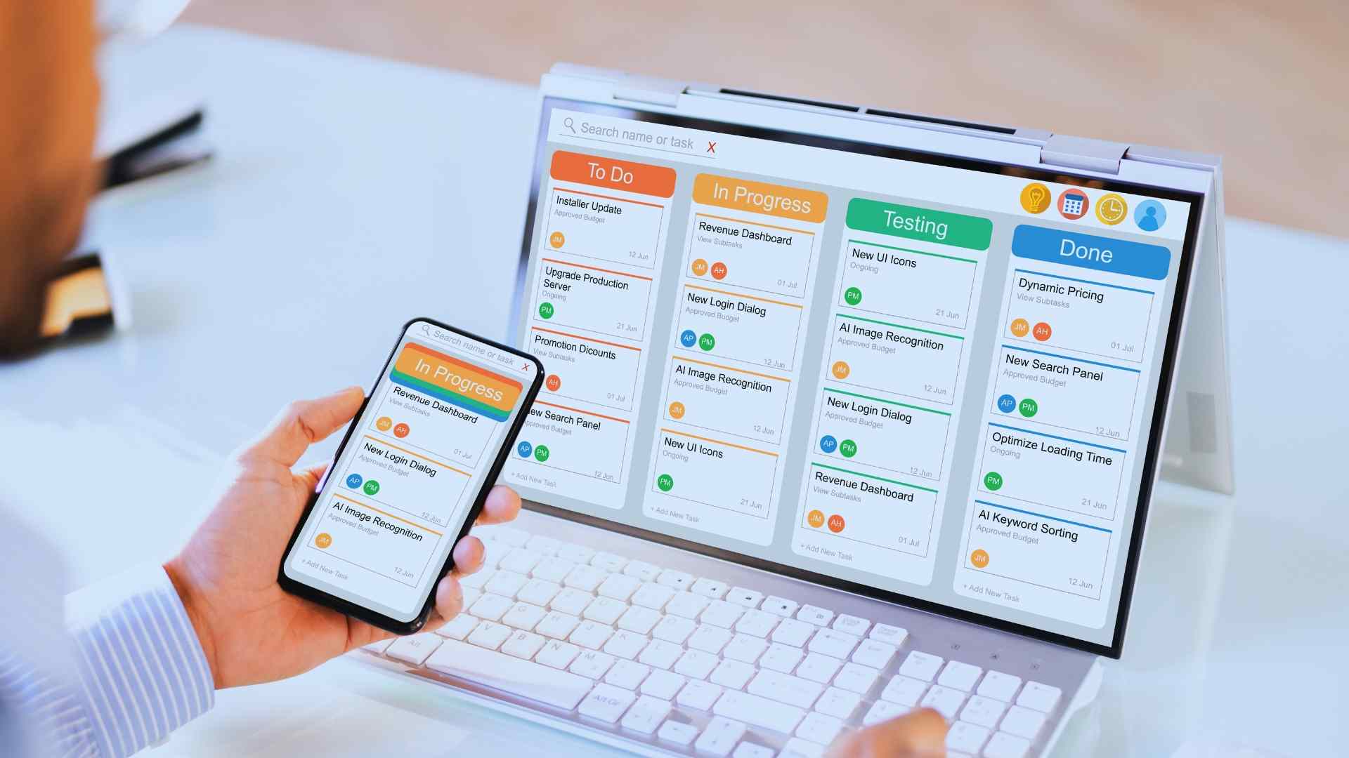 Close-up of a person holding a smartphone in sync with a laptop displaying a project management dashboard with tasks in various stages like 'To Do' and 'Done'.