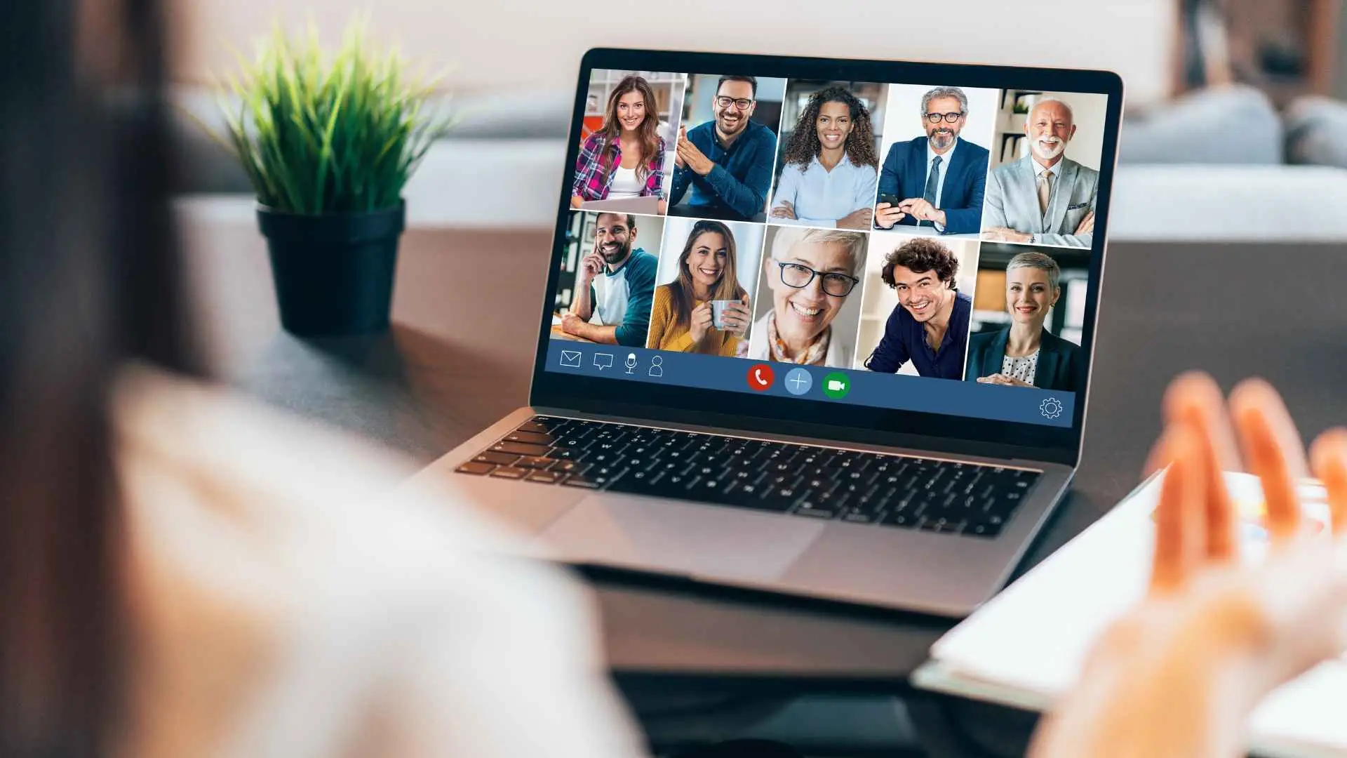 Diverse team of professionals smiling in an online virtual meeting, displayed on a laptop screen to signify remote collaboration and digital workplace solutions.