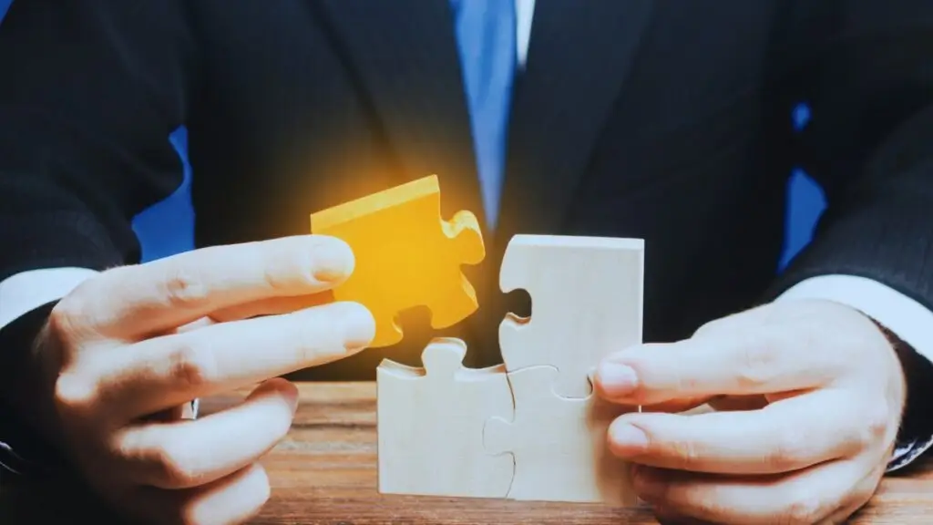 A businessperson assembling wooden jigsaw puzzle pieces, illustrating the problem-solving and strategic planning aspect of project management