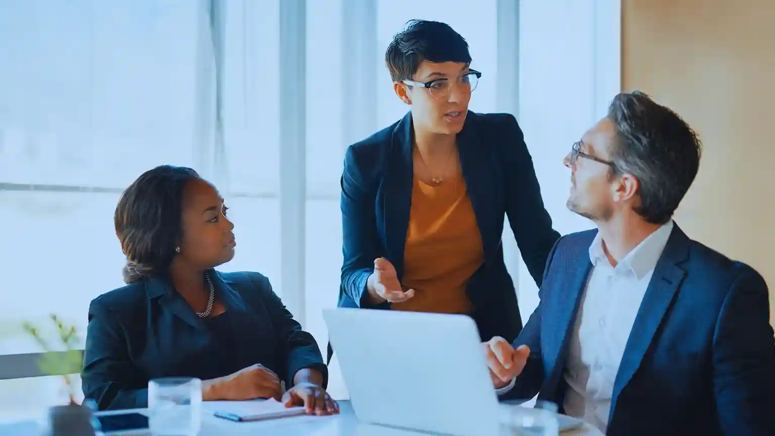 Business colleagues in intense discussion over a laptop, suggesting a collaborative strategy or problem-solving session.