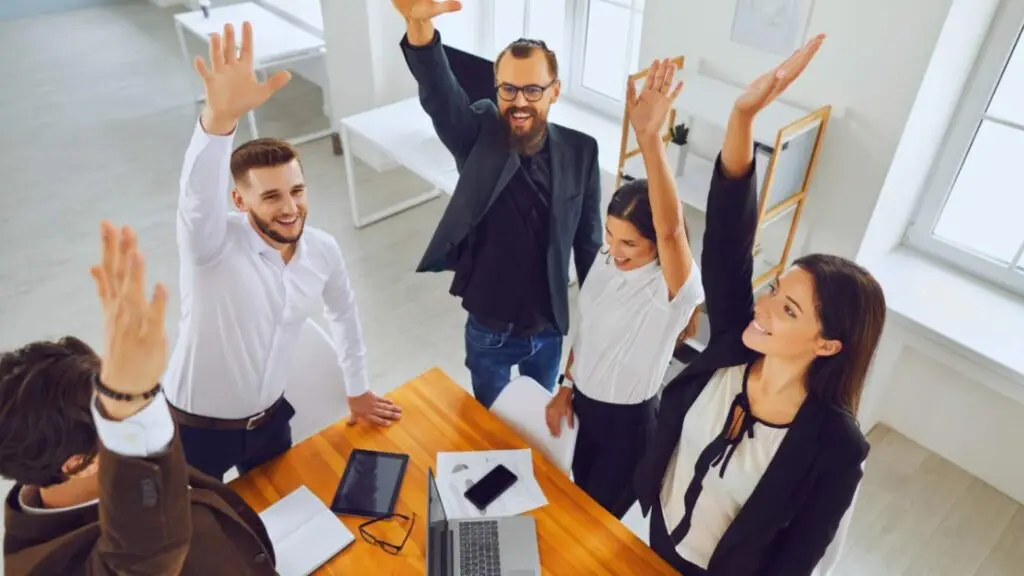 Elevated view of a business team celebrating a successful project, hands raised in a high five, embodying teamwork and achievement in the workplace
