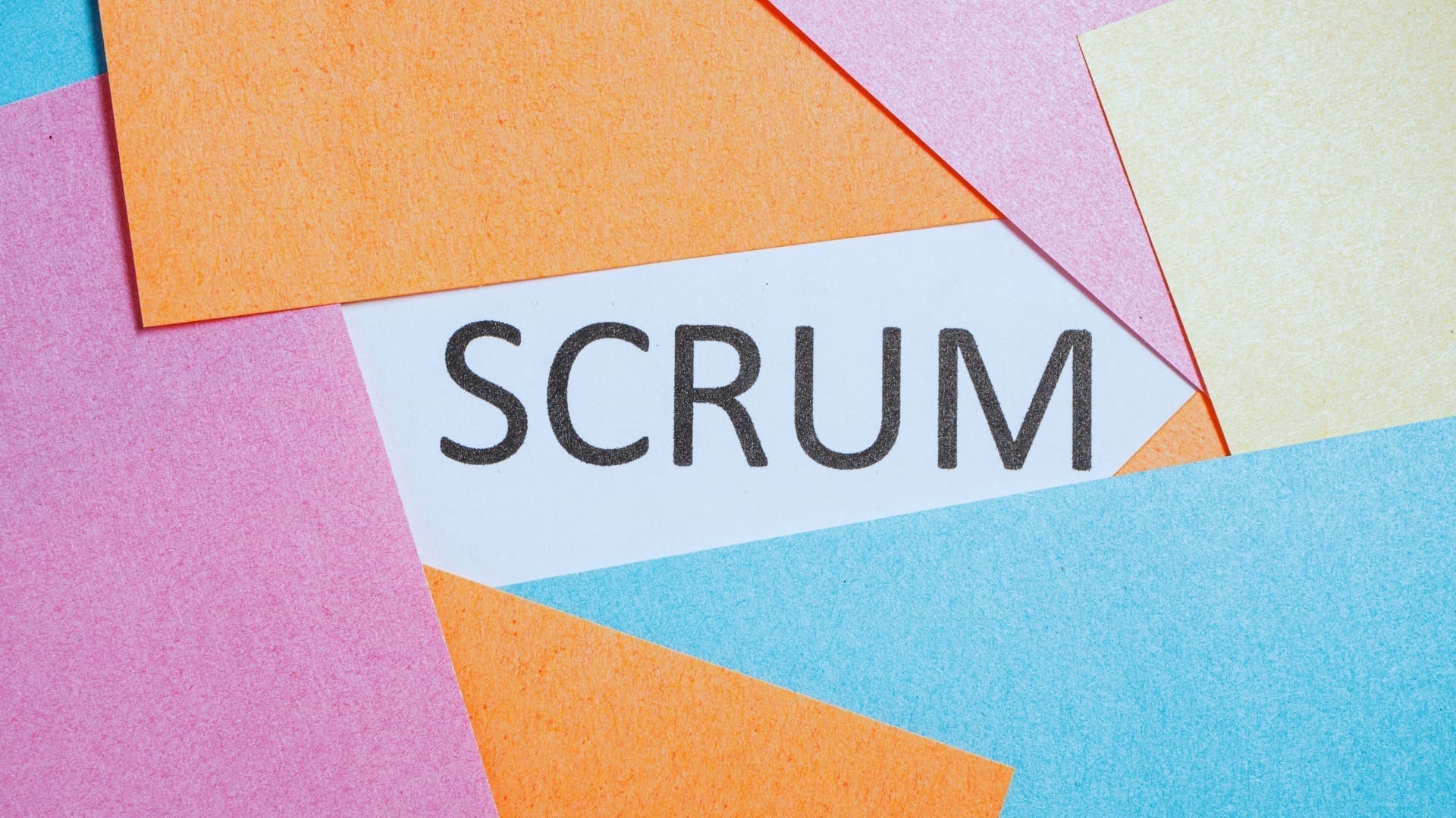 The word 'Scrum' surrounded by colorful sticky notes, representing the daily scrum process