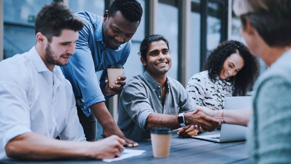 A group of diverse professionals collaborating and shaking hands during a meeting, illustrating teamwork and productivity, highlighting the effectiveness of Notion. Is Notion good for enhancing collaboration in the workplace?