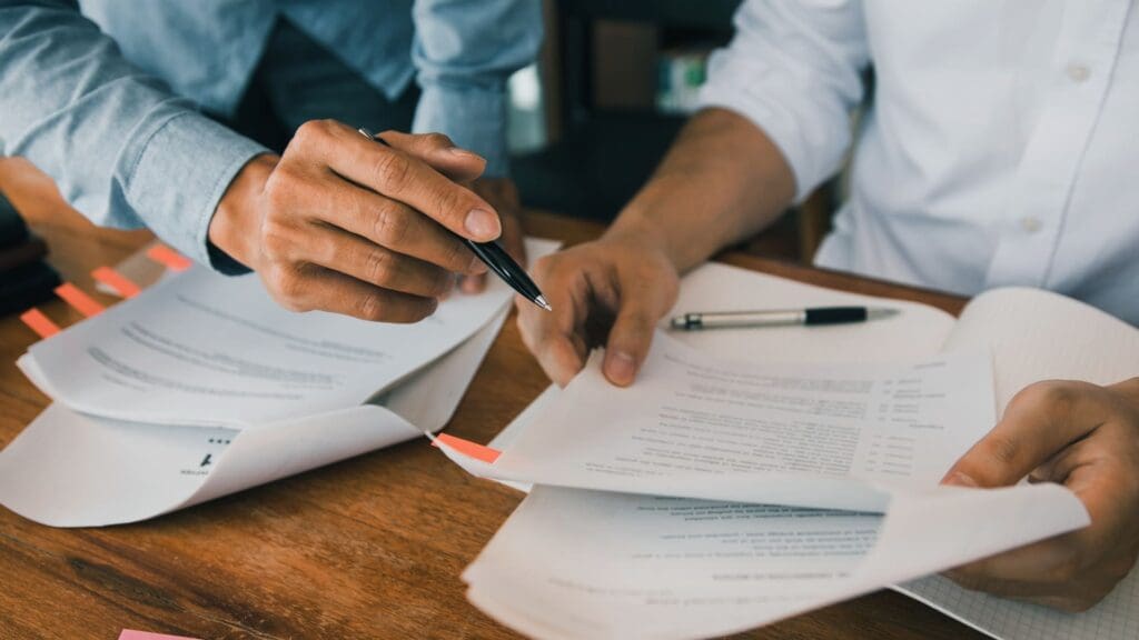 Two professionals reviewing documents together, discussing 'Is Notion worth it' in a work setting.