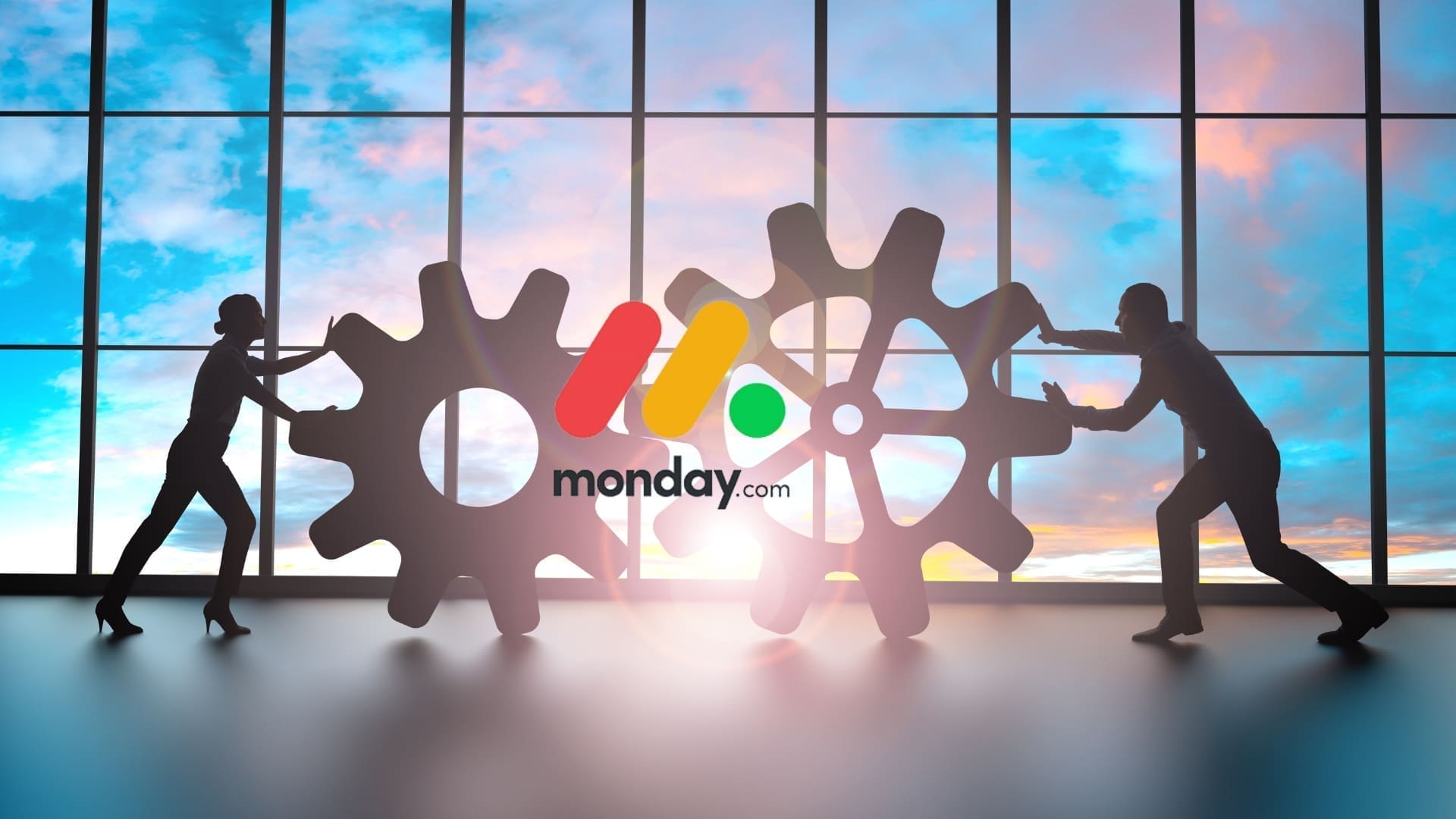 Silhouettes of two people pushing large gears towards each other in front of a large window with a sunset sky. The "monday.com" logo, highlighting their Free Plan, is centered in front of the gears, depicting collaboration and movement.