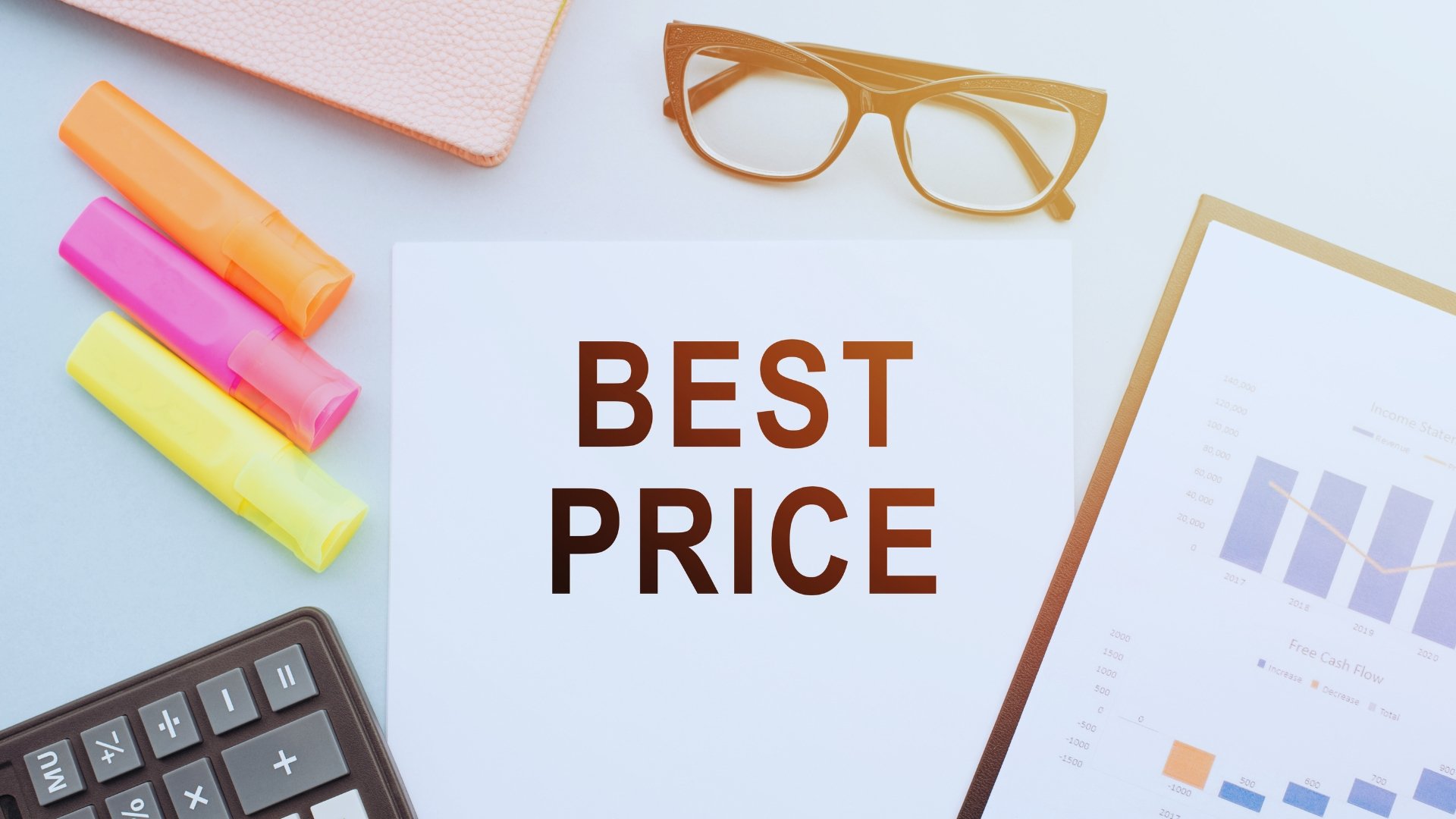 A paper with the words "BEST PRICE" is surrounded by highlighters, glasses, a notebook, a calculator, and a document with charts—hinting at SmartSuite Pricing—arranged on a light-colored desk.
