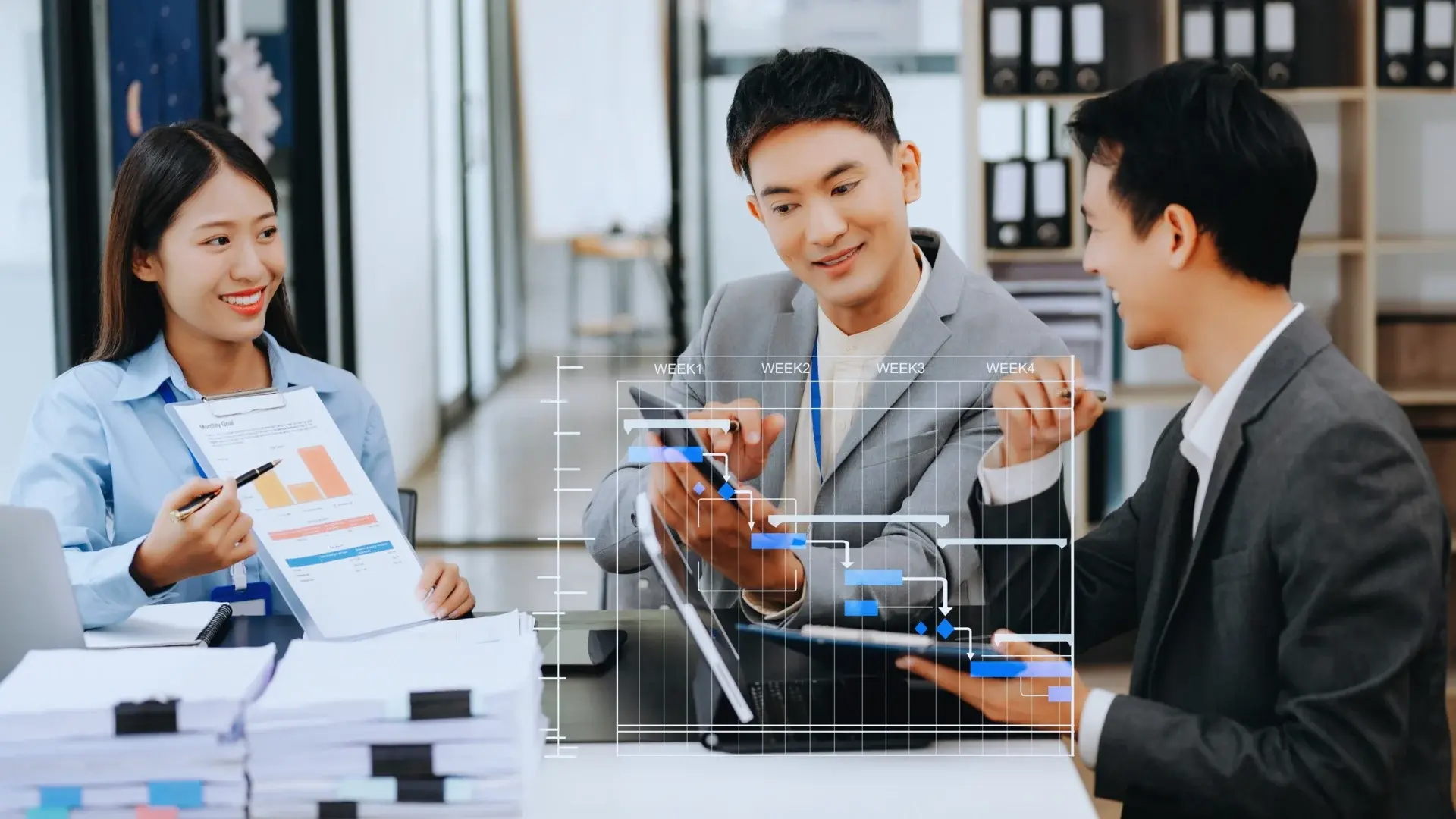 Three business professionals discuss a project using a tablet, showcasing the functions of project management office with a digital Gantt chart overlay and papers on the table, in a modern office setting.