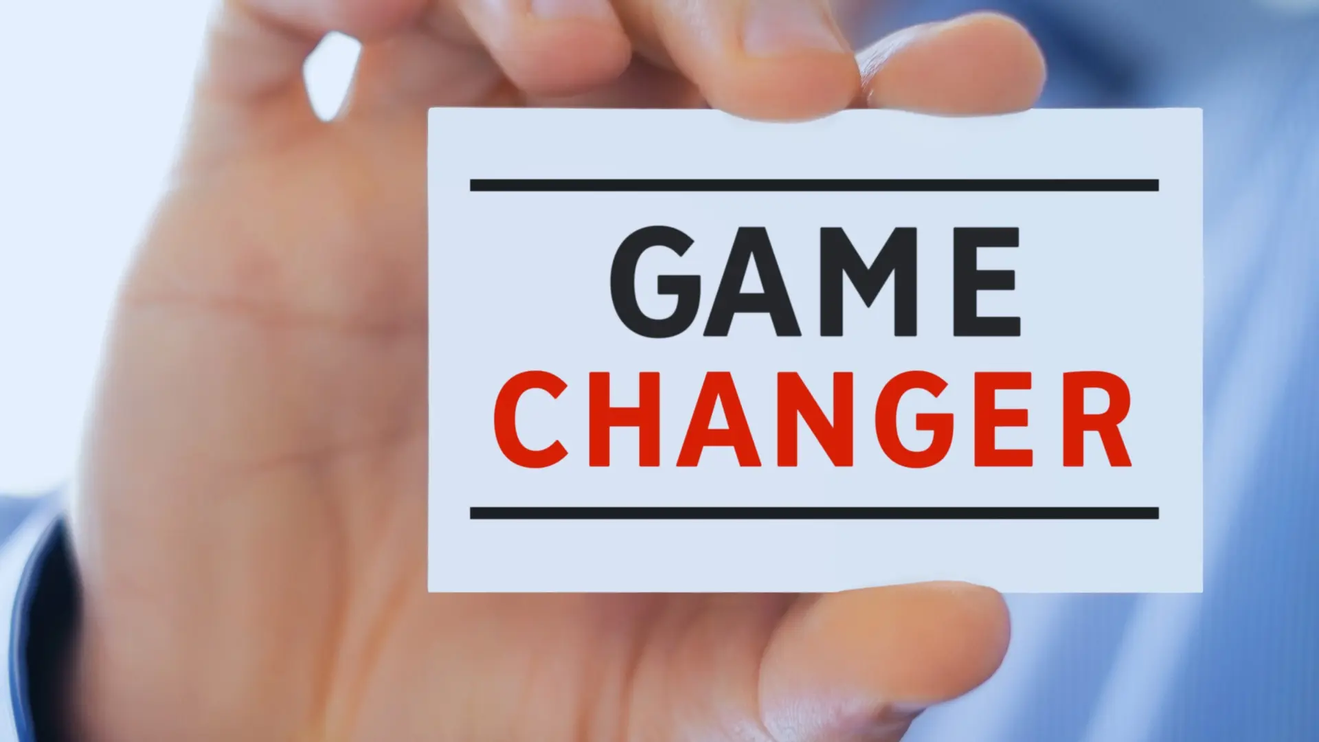 A person holds a white card close to the camera with the words "GAME CHANGER" in bold, underlined text—reflecting how the functions of project management office can redefine success within any organization.