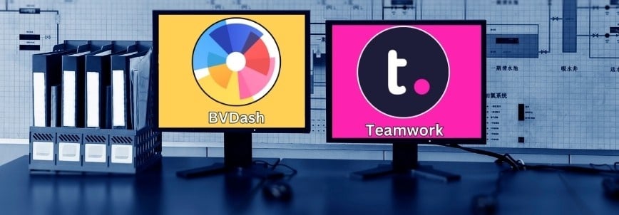 Two computer monitors display BVDash vs Teamwork.com—BVDash on the left with a colorful chart, Teamwork on the right with the "t" icon. Several ring binders are neatly lined up next to the monitors.