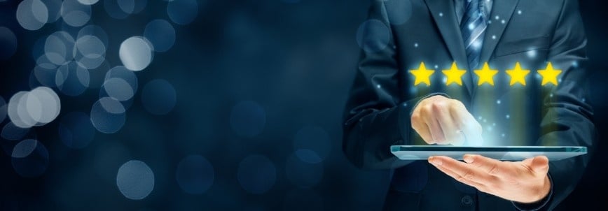 A person in a suit uses a tablet, with five glowing yellow stars floating above it, symbolizing a BVDash Review and excellent service. The dark, blurred background features bokeh lights for a modern touch.