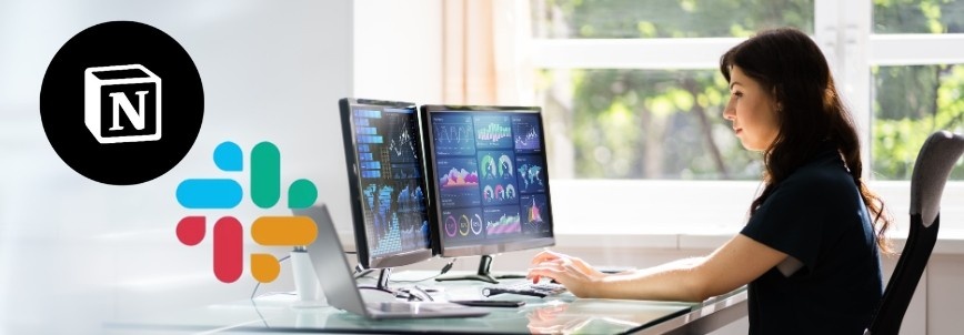 A woman works at a desk with two monitors displaying data and charts, highlighting seamless Notion Slack integration. The Notion and Slack logos are in the foreground as sunlight streams through the window behind her.