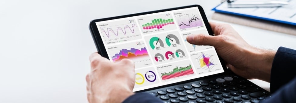 A person using a tablet with a keyboard, displaying colorful data analytics charts and Gantt Charts in BVDash on the screen, showing various statistics and performance metrics.