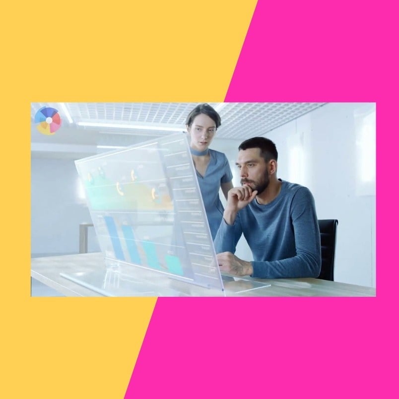 A man sits at a transparent computer screen analyzing data in BVDash, while a woman stands beside him observing. The modern office scene, framed by a pink and yellow diagonal background, highlights efficient task management in BVDash.