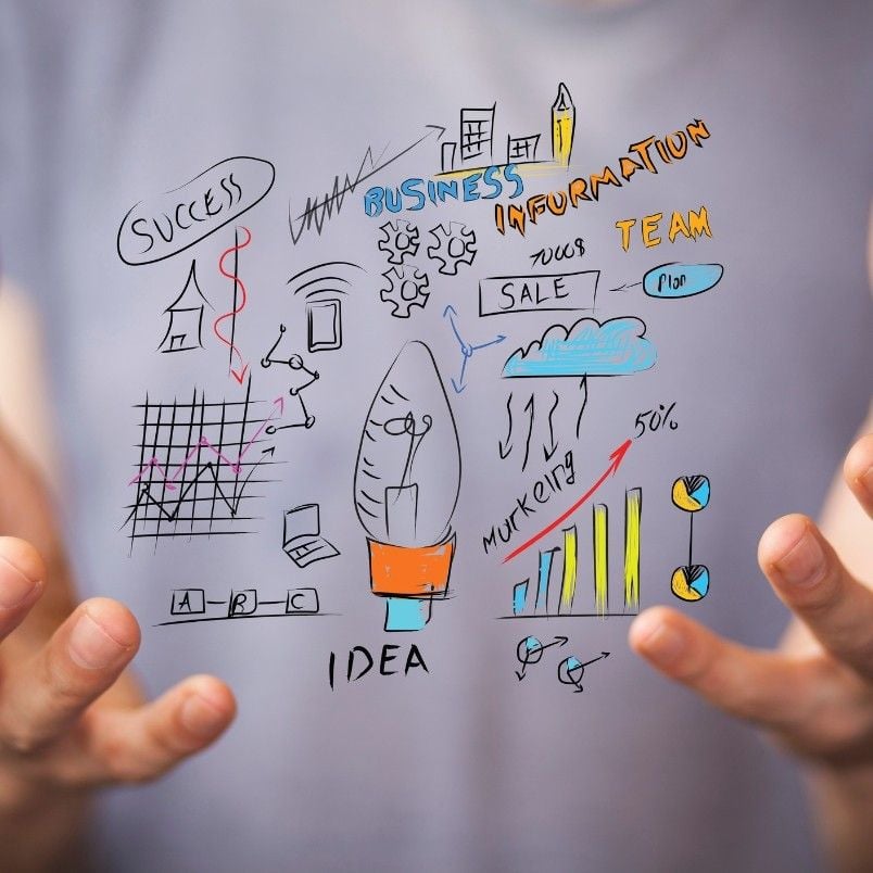A person holds out their hands with various colorful business-related doodles, such as charts, graphs, gears, and words like "success," "idea," and "marketing," symbolizing concepts like Agile Epic vs Feature in dynamic teamwork.