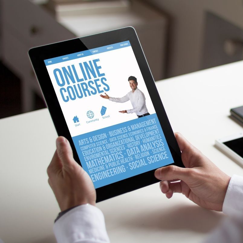A person holds a tablet displaying an "Online Courses" webpage with a smiling instructor, icons, and subjects like engineering, business, and math—plus details on CAPM® Certification Cost—all in eye-catching blue text.