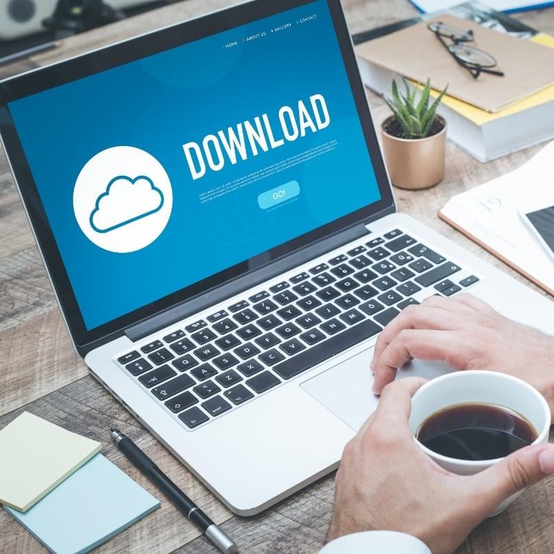 A person holding a coffee cup sits at a desk with a laptop displaying a large "DOWNLOAD" button, a cloud icon, and an open story map template. Office supplies, a notebook, and a small potted plant are also on the desk.