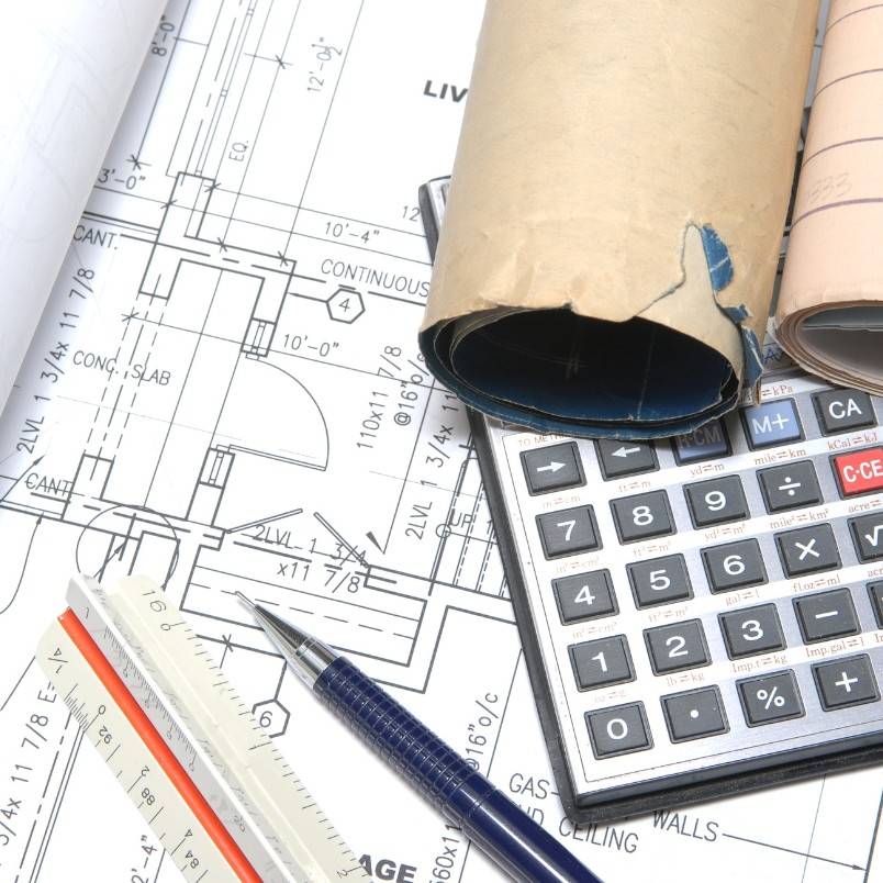 A close-up of architectural blueprints with a rolled-up plan, calculator, pen, and triangular scale ruler placed on top, illustrating the precision and organization essential in Construction Project Management.