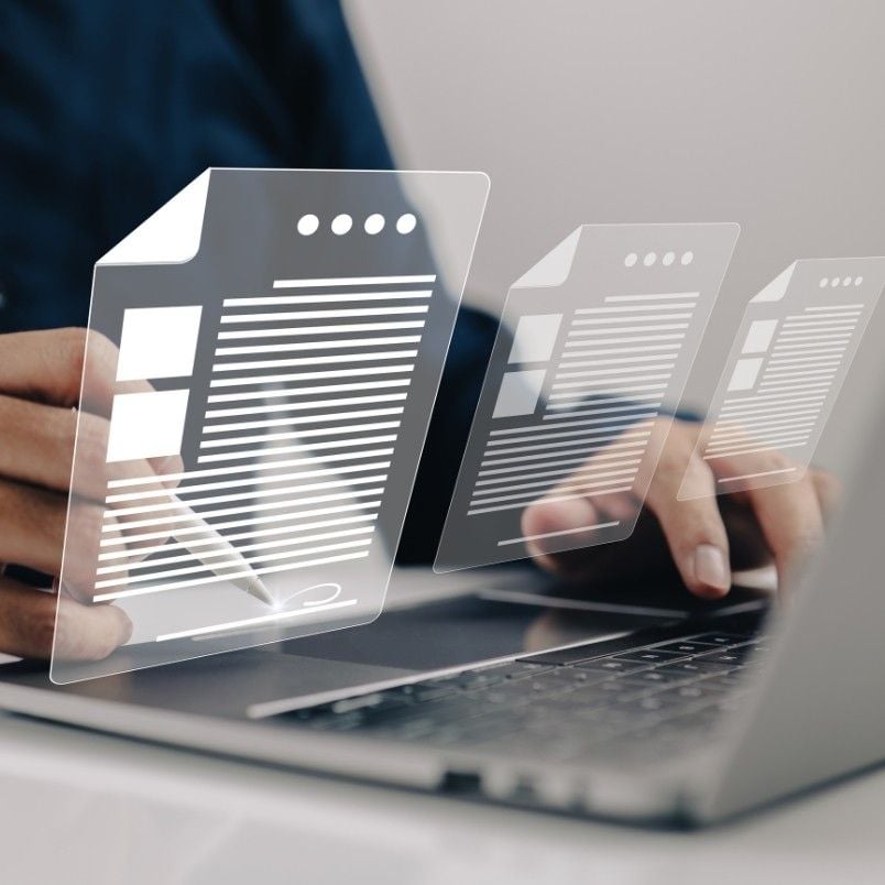 A person uses a laptop with floating digital document icons, representing e-signature, contract management, or online document management, and holds a stylus to interact with the virtual documents.