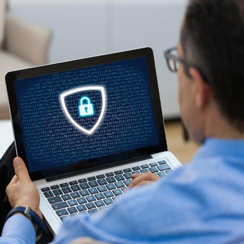 A person using a laptop displaying a digital lock icon inside a shield, representing cybersecurity and the secure use of generative AI in project management, with numbers and code in the background.