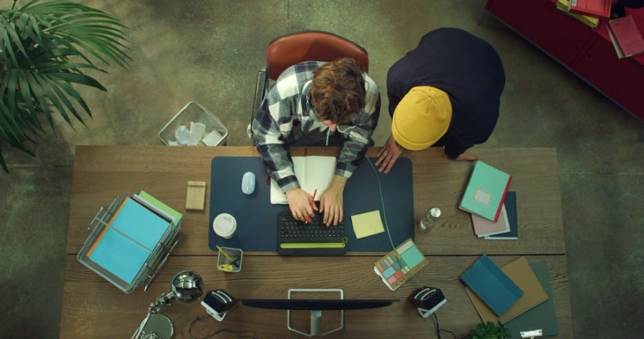 Overhead view of two colleagues reviewing study notes at a desk